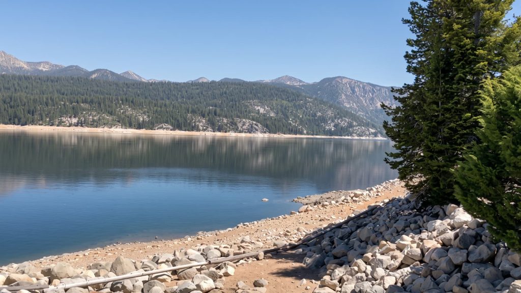 Lake Edison in the Sierra National Forest, with a rocky shoreline, pine-covered slopes, and High Sierra peaks in the distance